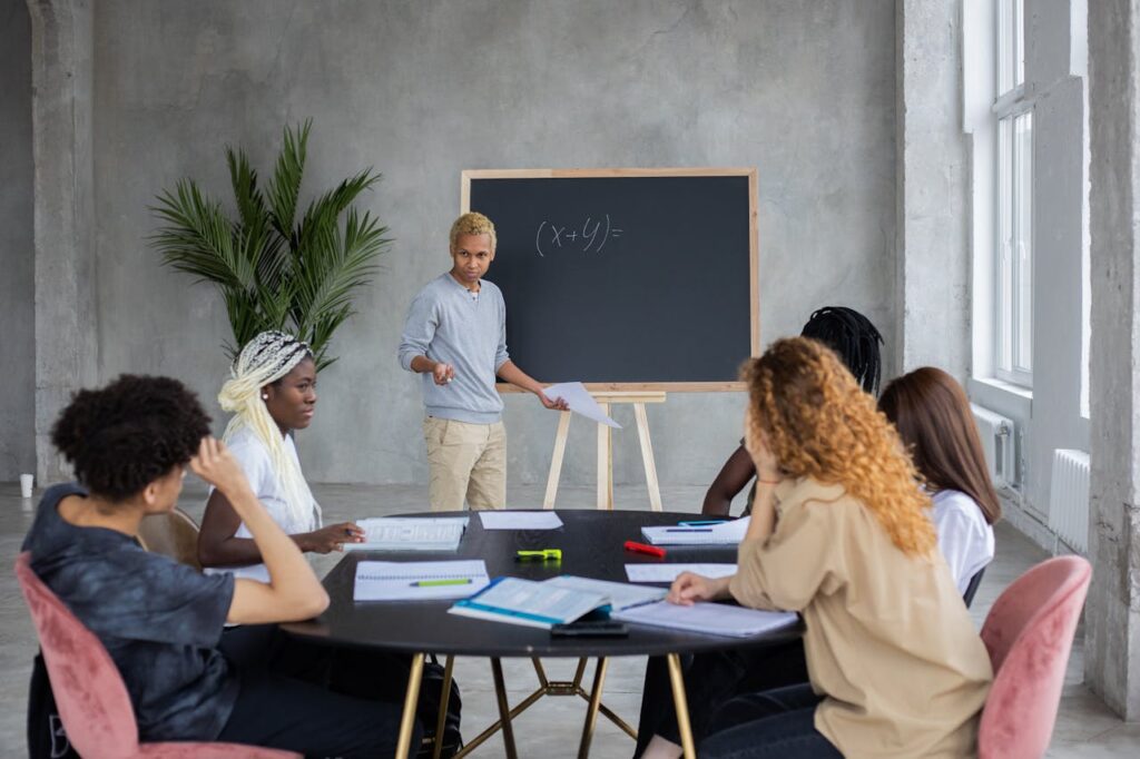 African American student explaining mathematic equation to diverse classmates while doing homework together in spacious room